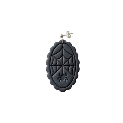 A black oval dangle earring featuring an embossed spiderweb design and a small spider motif near the bottom, suspended from a silver post against a plain white background.