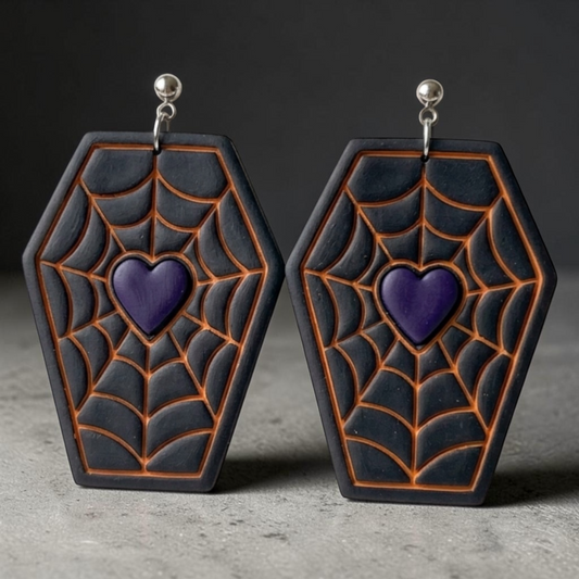 A pair of coffin-shaped earrings with a black and dark gray spiderweb pattern outlined in orange, featuring a purple heart in the center and silver-tone hooks.
