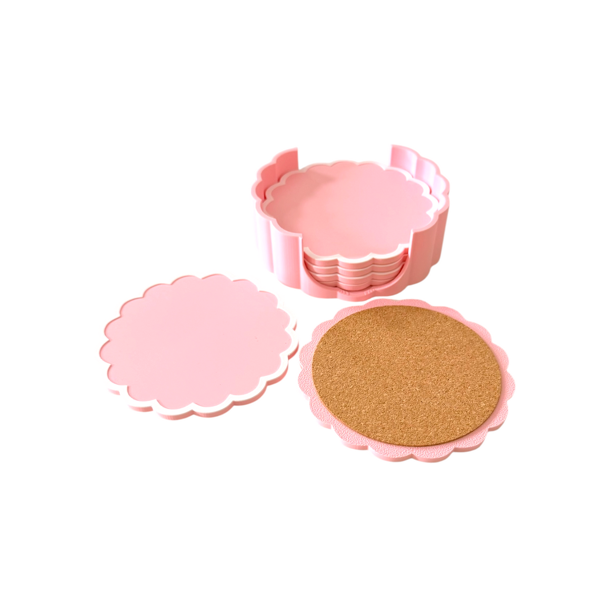 Pink scalloped coasters shown on a white background, including a stack of round coasters in a holder, one flat coaster, and one coaster with a cork insert.