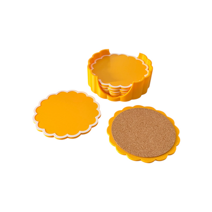 A set of scalloped circular coasters in bright yellow, shown with one stack, one coaster removed, and one coaster displaying a cork insert. Photographed on a clean white background.