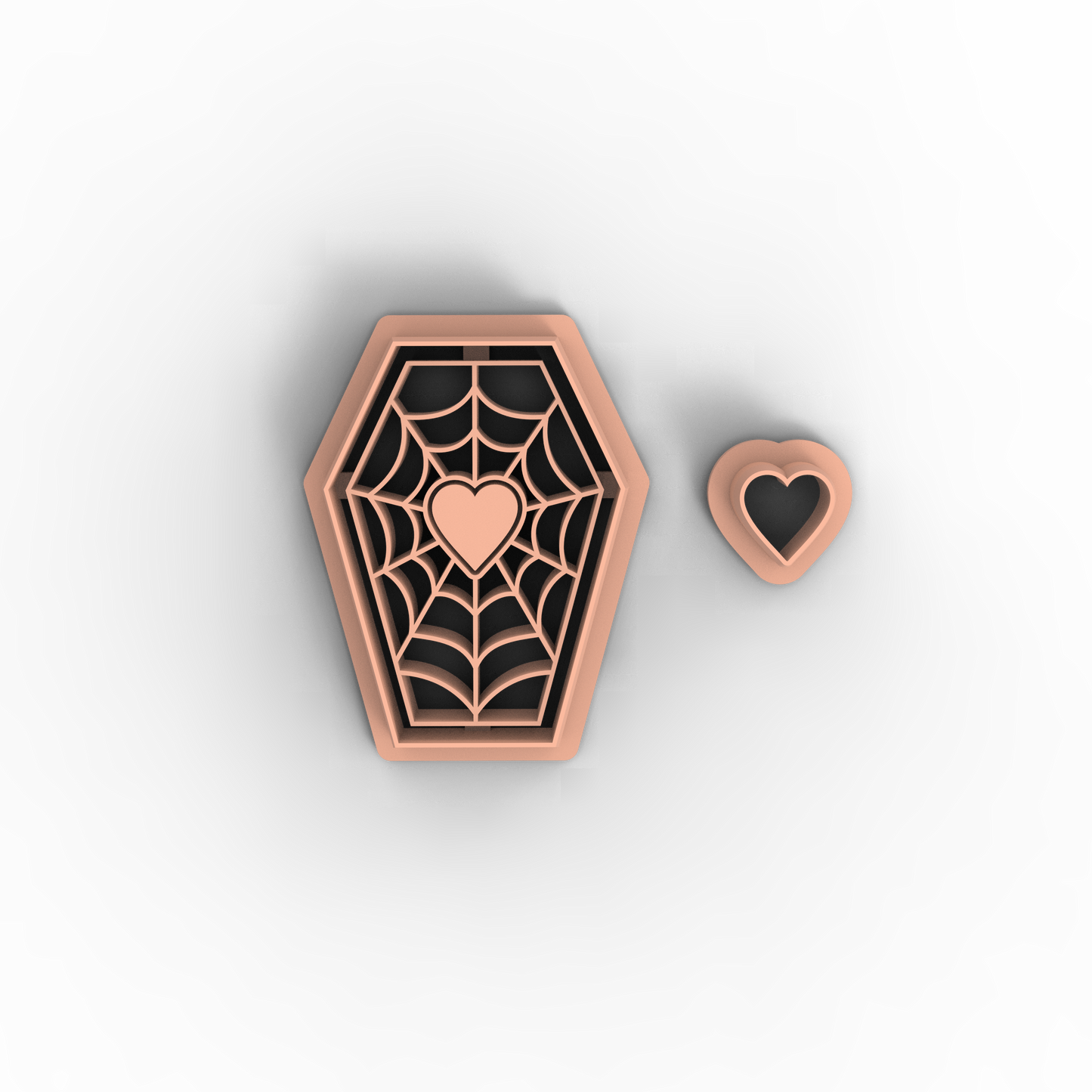A coffin-shaped polymer clay cutter with an engraved spiderweb pattern and a small heart in the center, shown next to a matching small heart-shaped cutter on a light gray background.